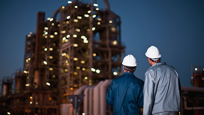 Image of two Grace employees looking at a Refinery plant